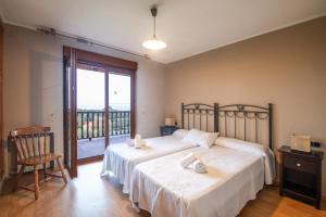 a bedroom with two beds and a balcony at Complejo Rural El Mirador de Ovio in Cuevas
