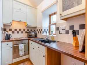 a kitchen with white cabinets and a sink at The Cottage - Uk45459 in Loftus