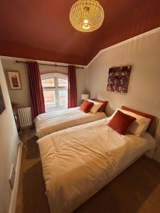 a bedroom with two beds and a chandelier at Peacock Cottage Eaton Road in Hough Green