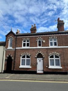 a brick building with a white door on a street at Peacock Cottage Eaton Road in Hough Green