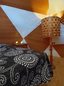 a bedroom with a black and white bed and a lamp at DOMO Ecológico in Curacautín