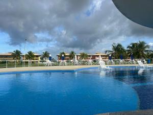 a large swimming pool with white chairs in a resort at Condomínio Villa das Águas Litoral Sul de Sergipe in Estância