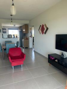 a living room with a red chair and a tv at Condomínio Villa das Águas Litoral Sul de Sergipe in Estância