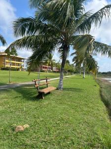 a park with a wooden bench next to a palm tree at Condomínio Villa das Águas Litoral Sul de Sergipe in Estância