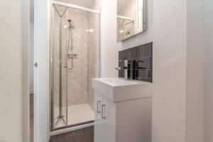 ein weißes Badezimmer mit Waschbecken und Dusche in der Unterkunft Hafan-Glan-Mor in Barmouth + 25 Fotos