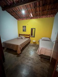 Un dormitorio con dos camas y una pared amarilla. en Chácara Serra Dourada, en Mulungu