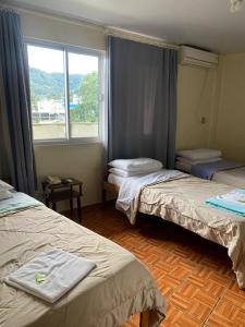a small room with two beds and a window at Hotel Schreiber in Rio do Sul