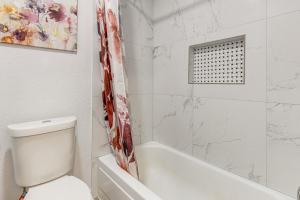 a white bathroom with a toilet and a bath tub at Families Welcome! Recently Renovated Home in Katy in Katy +21 photos