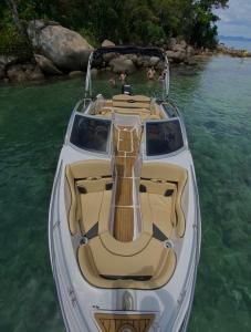 ein weißes Boot mit einer Gitarre im Wasser in der Unterkunft Aluguel de Lancha em Angra in Angra dos Reis