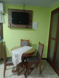 a dining room with a table and chairs and a tv at Refúgio familiar in Canela
