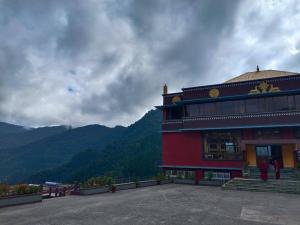a red building with mountains in the background at The Jhandi Nest in Gorubathān