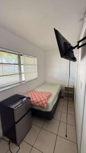 a small bedroom with a bed and a television in it at Hallandale Urban Rooms in Hallandale Beach