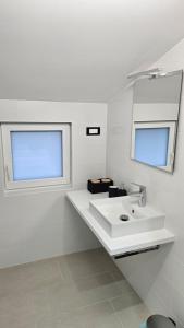a white bathroom with a sink and a mirror at Apartment Kompara in Ajdovščina +1 photo