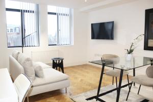 a living room with a white couch and a glass table at Chelmsford Town Centre, Modern 1 Bed Apartment in Chelmsford