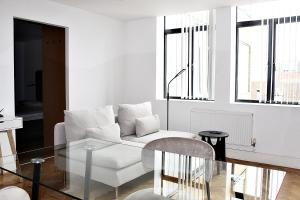 a living room with a white couch and a glass table at Chelmsford Town Centre, Modern 1 Bed Apartment in Chelmsford