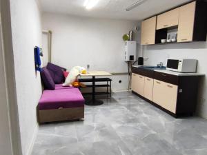 a living room with a purple couch and a kitchen at Guest house Gosling in Almaty