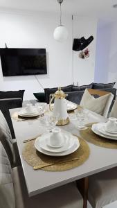 a white table with plates and glasses on it at Apt aconchegante perto do shopping in Petrolina