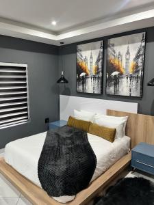 a bedroom with a bed with three pictures on the wall at 98 Inn Guesthouse Two Bedroom Apartment in Jacksonʼs Drift