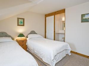 a bedroom with two beds and a mirror at Grebe Cottage in Dilham +3 photos