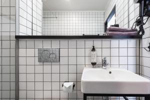 a white tiled bathroom with a sink and a mirror at Stary Rynek - Old Market Apartments Poznań in Poznań +36 photos