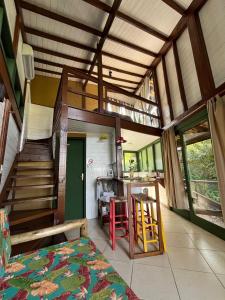 a room with a bed and a kitchen and a staircase at Bangalô Bambu in Imbituba