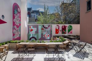 a patio with tables and chairs and paintings on the wall at Jill Hotel Brussels Centre Midi in Brussels