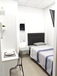 a white bedroom with a bed and a desk and a chair at Habitacion con entrada independiente y aire acondicionado, Centro Piura in Piura