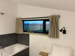 a bathroom with a bath tub and a window at Le Marzelheide 2 in Lontzen