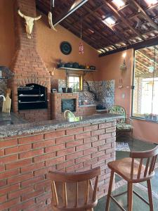 una barra de ladrillo con dos sillas y una chimenea en Chácara para Alugar Recanto dos Picutis, 