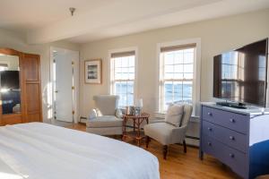 a bedroom with a bed and two chairs and a flat screen tv at The Beach House Inn in Kennebunk