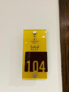 a yellow sign on a wall with a clock on it at رغدان فيو للشقق المخدومة in Al Baha
