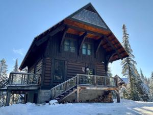 ein großes Blockhaus im Schnee mit Balkon in der Unterkunft Family escape w private hot tub in Lac-Superieur