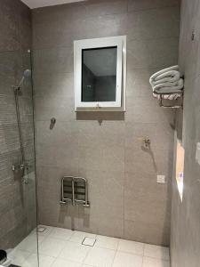 a bathroom with a shower with a television on the wall at رغدان فيو للشقق المخدومة in Al Baha