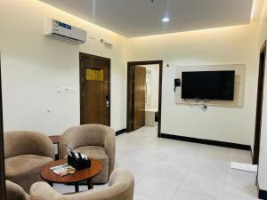 a living room with two chairs and a flat screen tv at رغدان فيو للشقق المخدومة in Al Baha