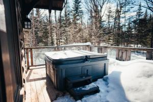 een houten terras met een met sneeuw bedekte kachel op een veranda bij Be zen with nature & enjoy private hot tub in Lac-Superieur