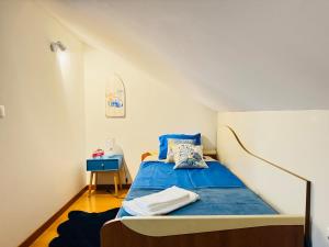 een kleine slaapkamer met een bed met blauwe lakens bij Beach House in Fão