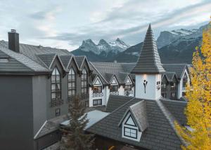 a building with a roof with mountains in the background at Everwild Canmore - Nordic Spa & Hotel in Canmore