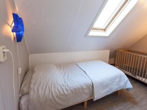 a small bedroom with a bed and a crib at Villa in Friesland with Garden by Water in Andijk +25 photos