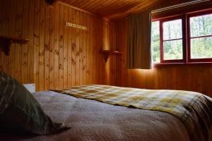 een bed in een houten kamer met een raam bij Casa Maqui Salto del Laja in Salto del Laja