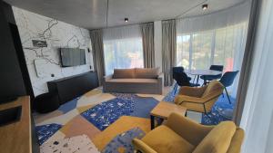 ein Wohnzimmer mit Fernseher, Couch und Sesseln in der Unterkunft Apartament Słoneczny z aneksem Biała Perła Czarna Góra in Heudorf