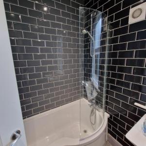 a black tiled bathroom with a shower and a tub at Gorgeous Town Centre 3-Bed 2-Bath Apartment Parking Available in Harrogate +20 photos