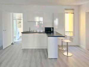 una cucina con mobili bianchi e un piano di lavoro nero di La Clé de Pierre a Saint-Germain-en-Laye