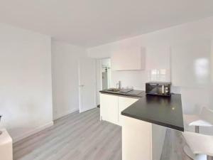 una cucina con mobili bianchi e un piano di lavoro nero di La Clé de Pierre a Saint-Germain-en-Laye