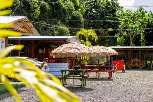 eine Terrasse mit einem Strohschirm, Tischen und Stühlen in der Unterkunft Blü Zen, Ideal Couple’s Stay in Mameyes Rio Grande in Mameyes