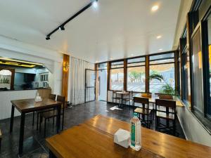 Un restaurante con mesas y sillas de madera y ventanas. en Navaya Residence, en Pātan