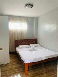 a bedroom with a bed with white sheets and a window at 2K2M Rental Units in Panglao