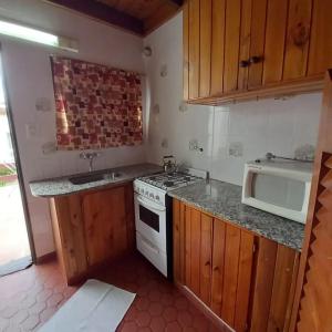 a small kitchen with a stove and a microwave at Complejo Antilhue in Las Grutas +3 photos