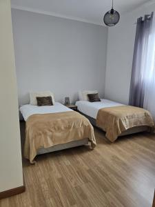 two beds in a room with white walls and wood floors at Casa da Cruz in Porto da Cruz