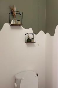 a bathroom with a toilet with two shelves on the wall at Résidence Les Oliviers, La Défense 20 mn, 4 to 6 people in Bezons