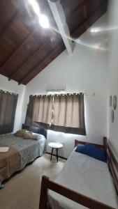 a bedroom with two beds and a table and a window at Casa 05 - Grande Família in Angra dos Reis